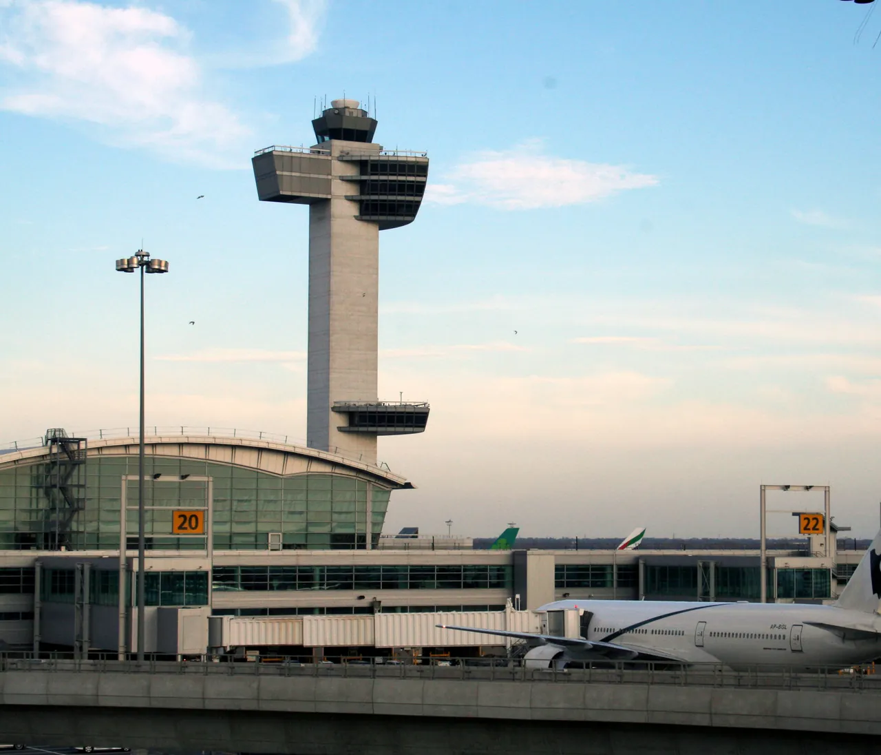 JFK control tower rising above Terminal 4 against a pale evening sky